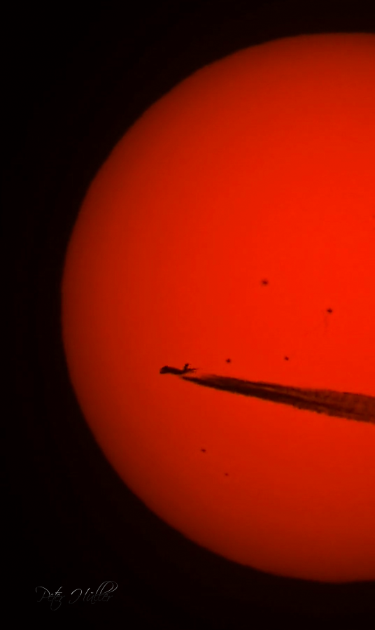 Sonne mit vorbeifliegendem Flugzeug